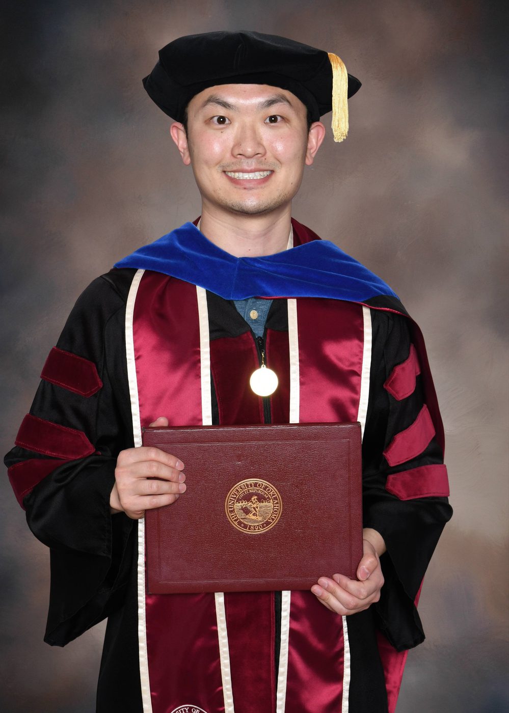 Mengye Chen holding his University of Oklahoma doctoral diploma